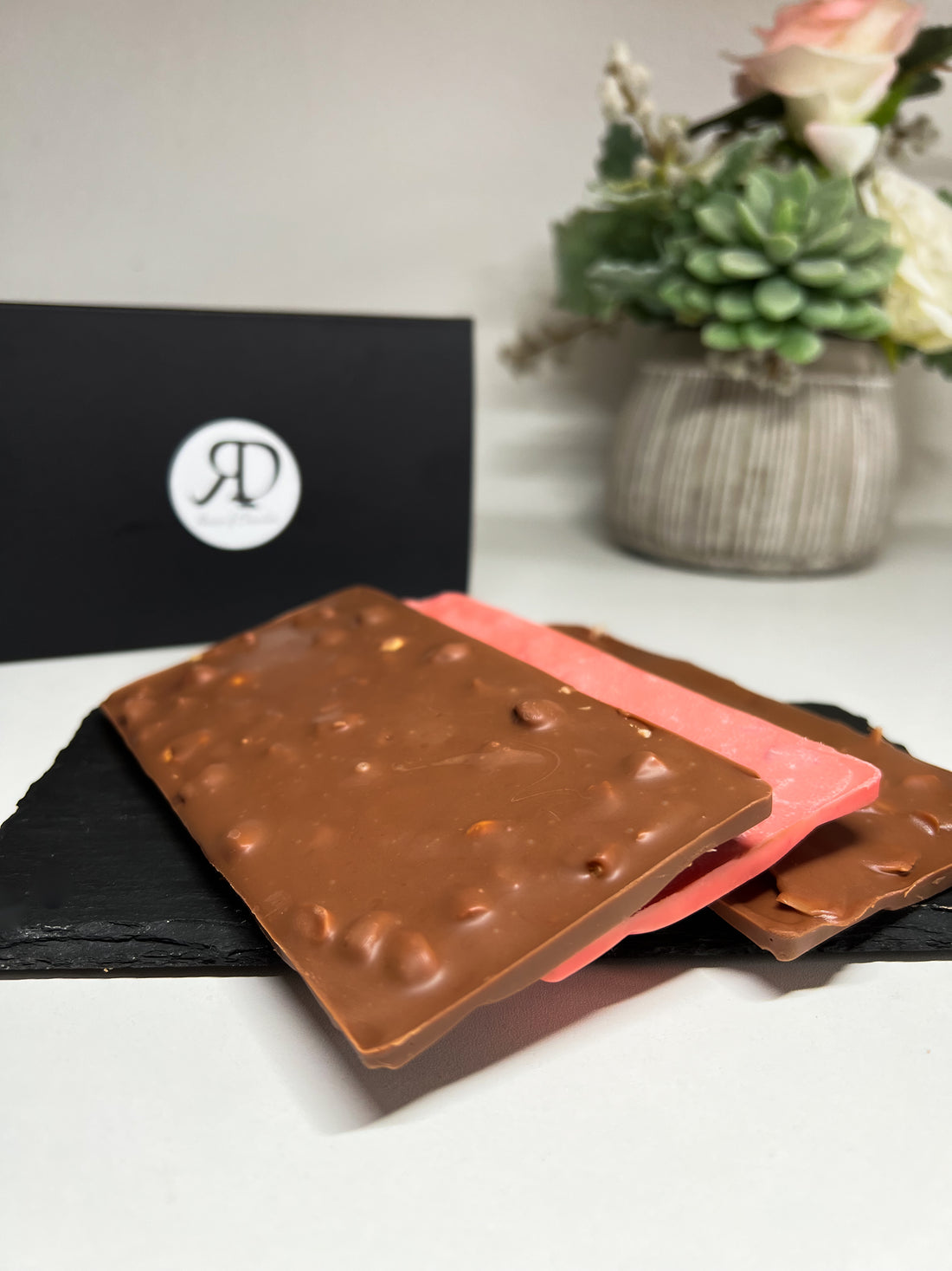 Delightful trio of Belgian milk chocolate bars - one filled with coconut, another with hazelnuts, and a pink variant brimming with juicy strawberries. A taste adventure awaits at RD House of Chocolate!