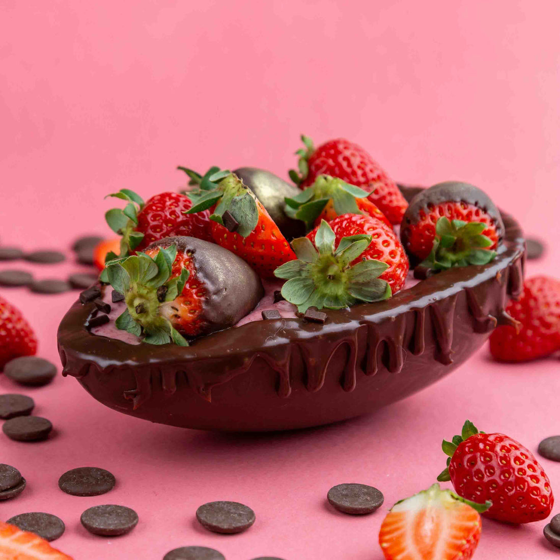 Chocolate-covered strawberries in a drizzled chocolate bowl on pink background.