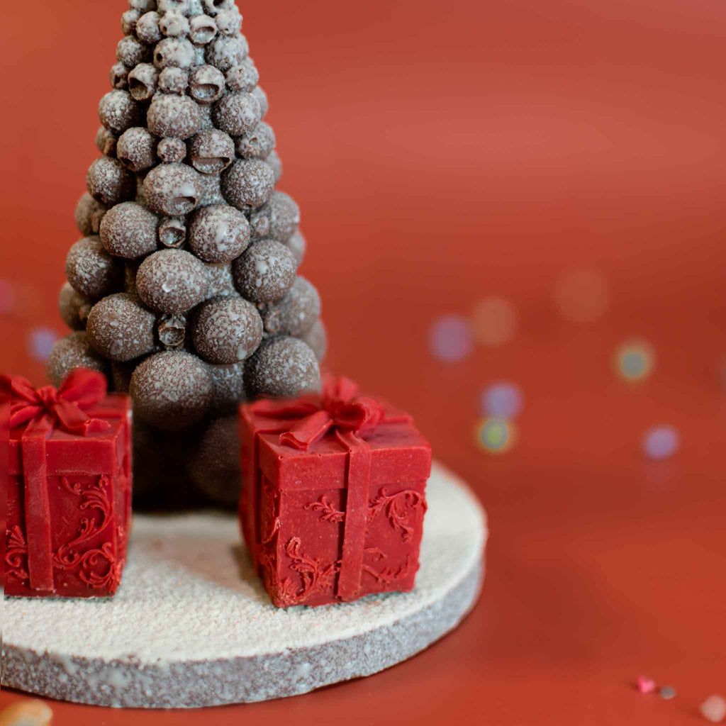 White velvet chocolate bubble tree on a plaque with two red chocolate gift boxes