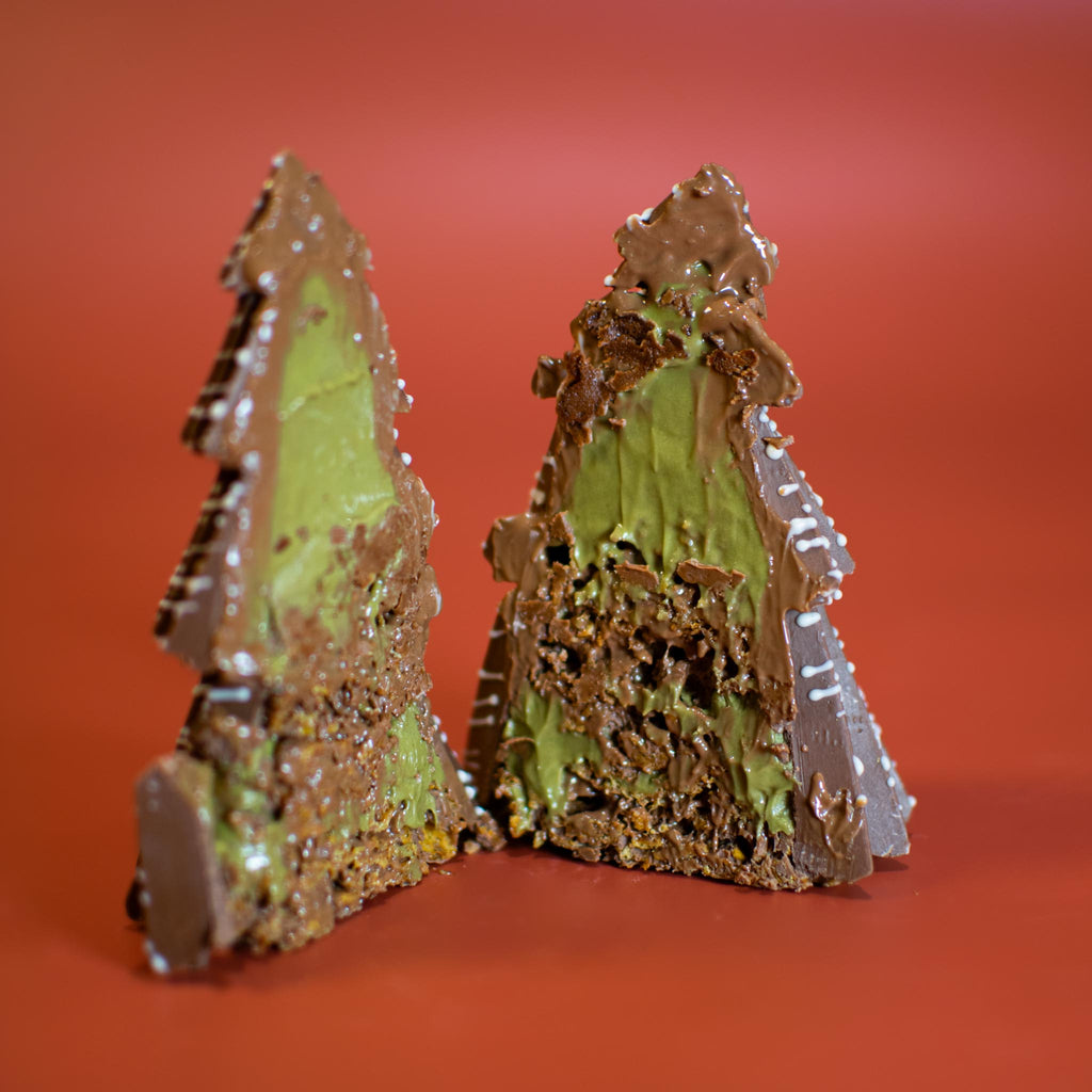 Little Christmas Tree cut in half, showing the pistachio spread and crispy filling inside the milk chocolate shell