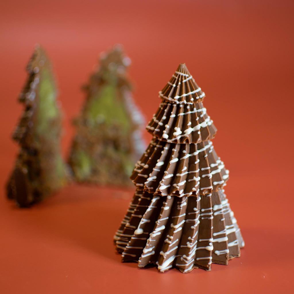 Whole Little Christmas Tree in milk chocolate with white drizzle, with two cut halves behind it