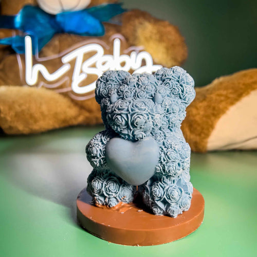 Azure Love bear in azure blue white chocolate, covered in a rose pattern and holding a heart, on a milk chocolate plaque