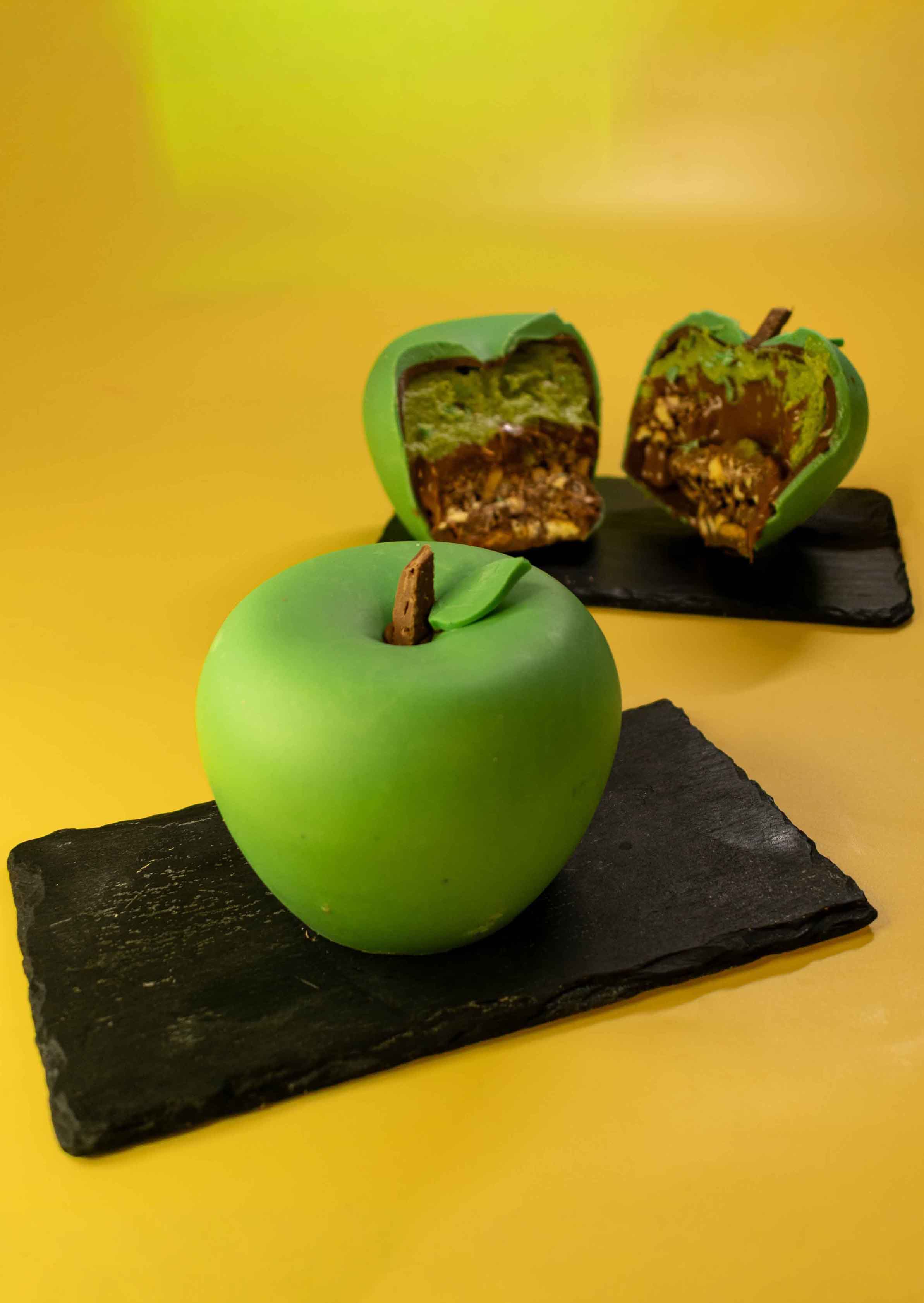 Green chocolate apple with edible chocolate stem and leaf on a slate board